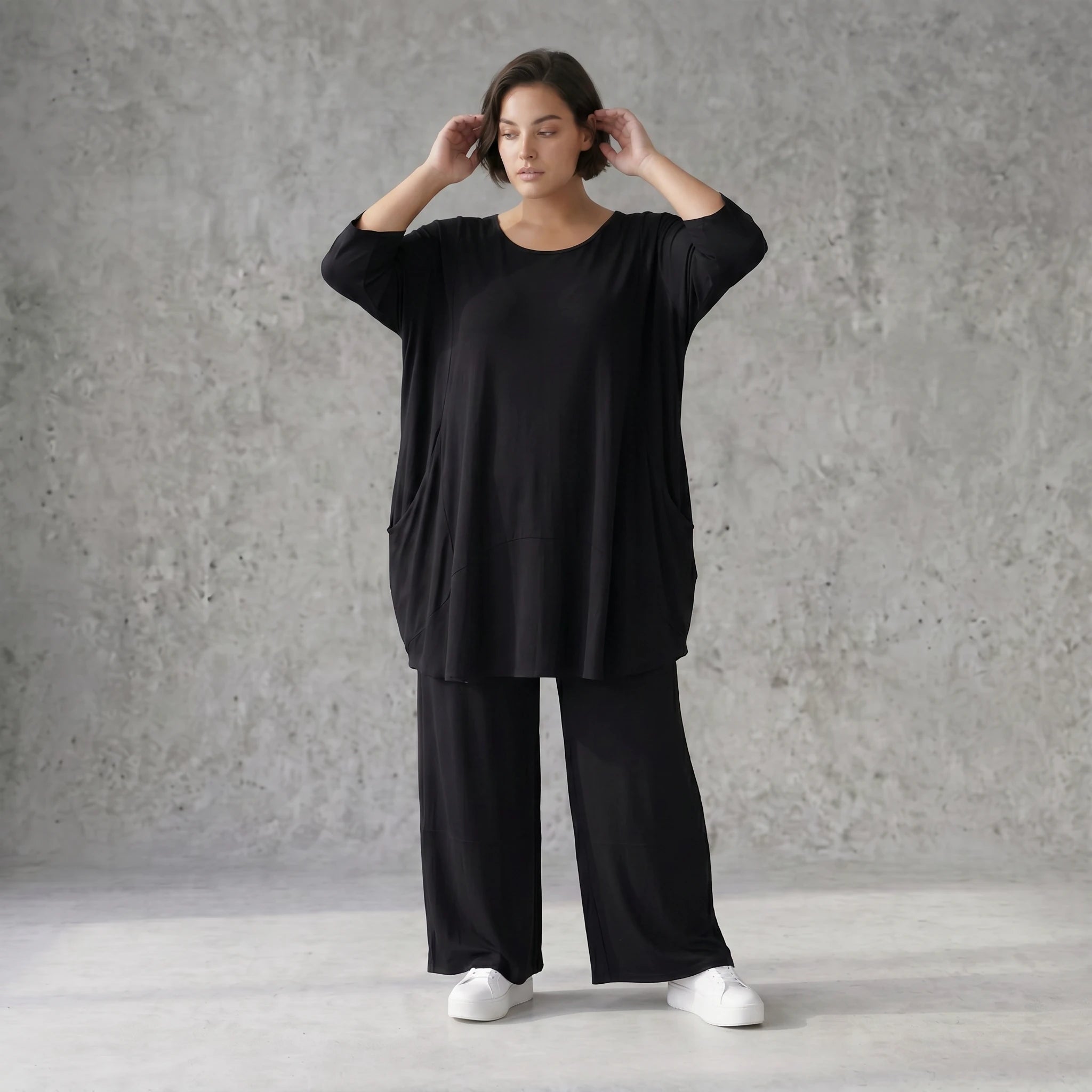 Fließendes Glockenshirt in tiefem Schwarz mit 3/4-Arm Rundhalsausschnitt und Nahttaschen