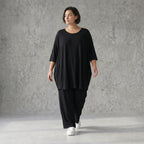 Fließendes Glockenshirt in tiefem Schwarz mit 3/4-Arm Rundhalsausschnitt und Nahttaschen