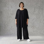 Fließendes Glockenshirt in tiefem Schwarz mit 3/4-Arm Rundhalsausschnitt und Nahttaschen