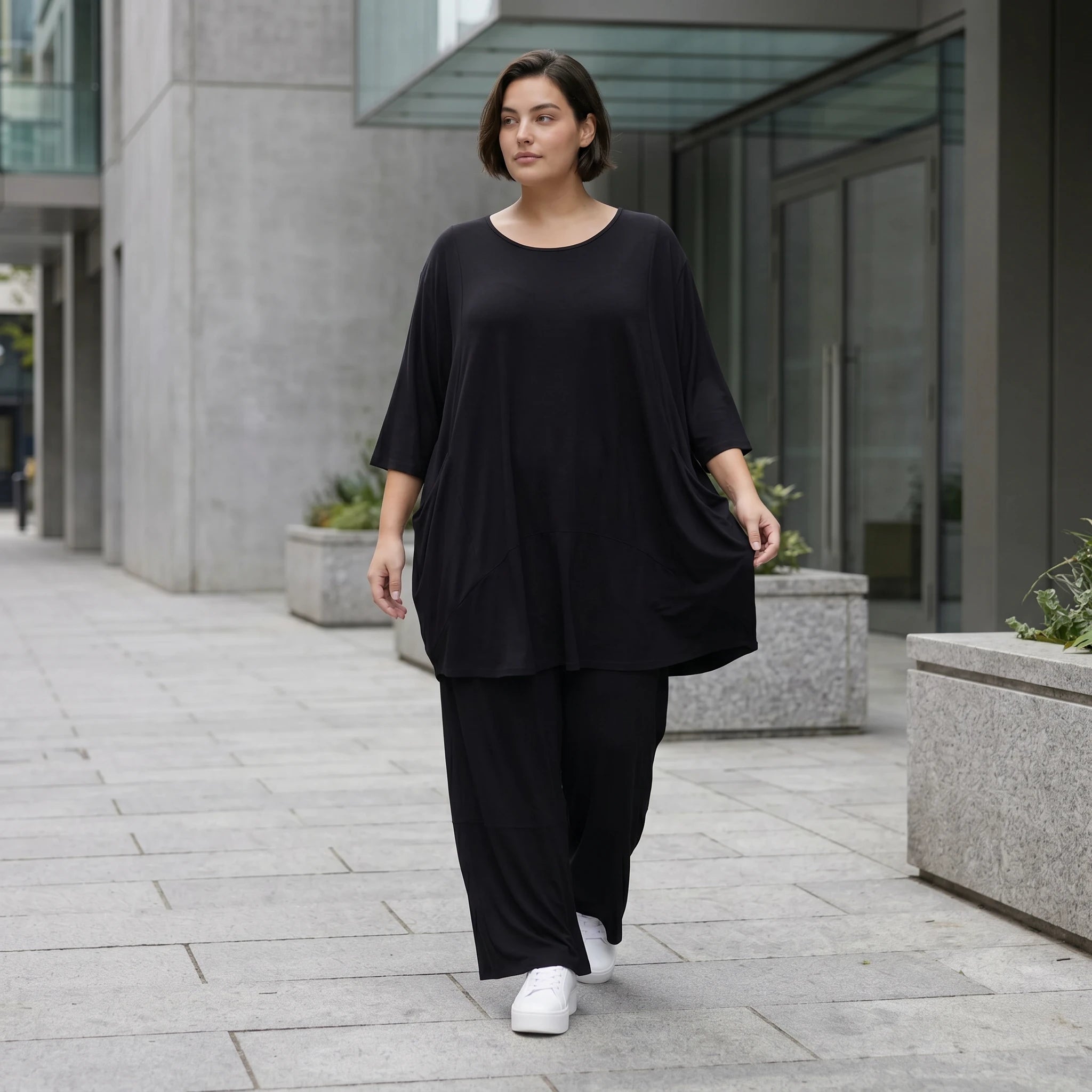 Fließendes Glockenshirt in tiefem Schwarz mit 3/4-Arm Rundhalsausschnitt und Nahttaschen